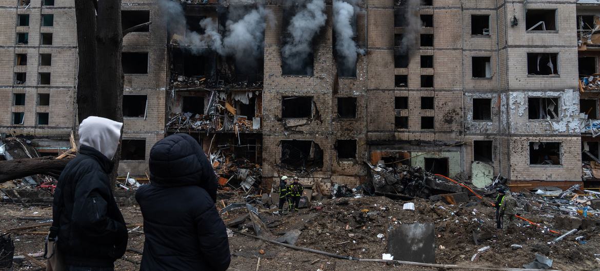 People watch a building on fire following a missile attack in Ukraine.